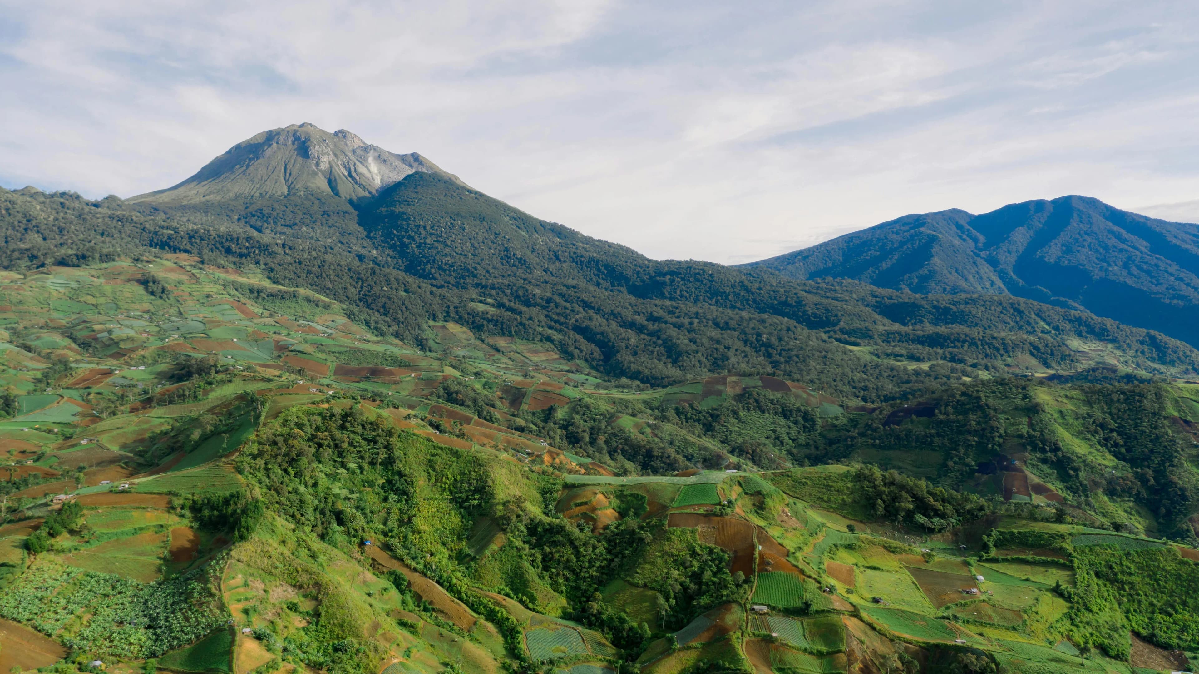 Aerial view of a Philippine volcano rising above terraced farmland and forested ridges